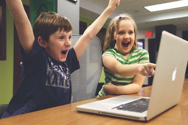 Image de deux enfants joyeux et étonnés devant un ordinateur.