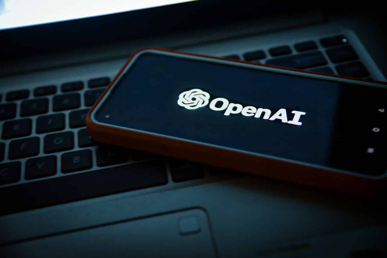 Un téléphone portable, posé sur un ordinateur, mondre l'écran d'accueil d'Open AI