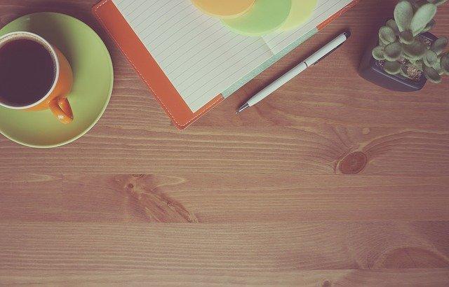Image d'une tasse de café et d'un carnet de notes sur un bureau en bois